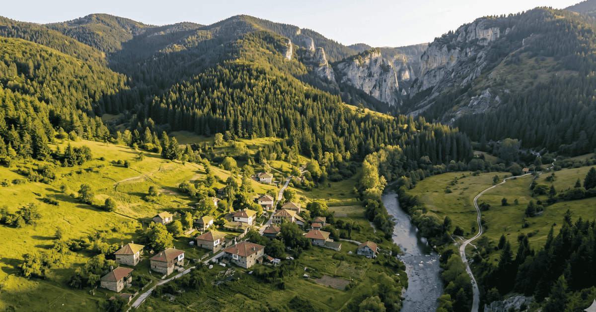 Panoramic view of the Rhodope Mountains in Bulgaria, with pine forests and a valley with a small village in the distance